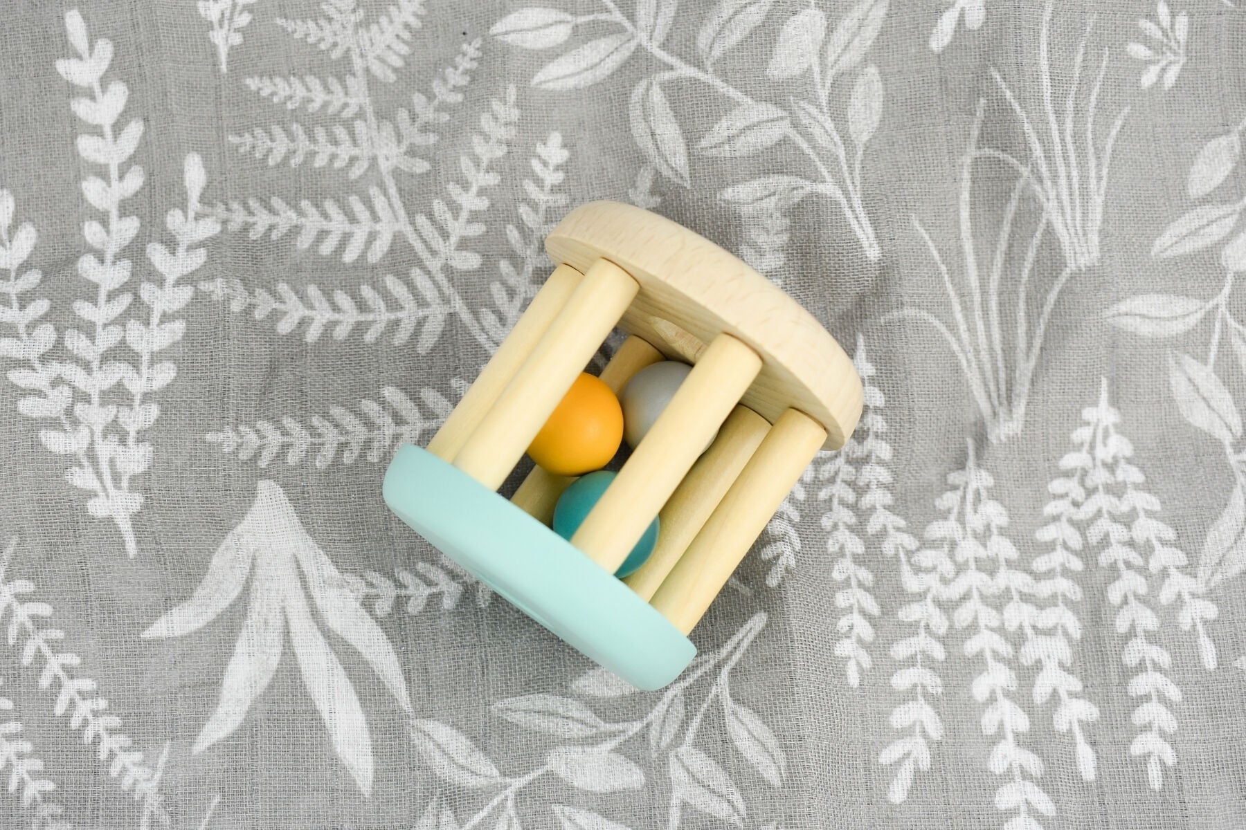 Mint green wooden rattle by Calm & Breezy for babies, featuring natural wood beads and soft twine for gentle sensory play.